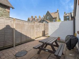 a wooden picnic table on a patio next to a fence at The Gables Studio in Keswick