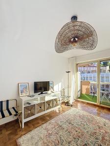 a living room with a television and a chandelier at Hello Menton in Menton