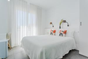 a white bedroom with a white bed with pillows at Hostal La Isla in Carboneras
