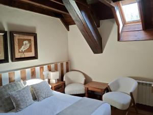 a bedroom with a bed and two chairs and a window at Hotel Rural Eseverry-Bosque Irati in Jaurrieta