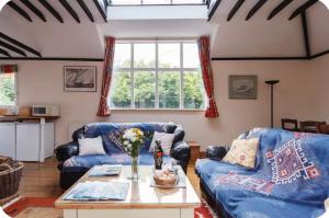 a living room with two blue couches and a table at Spout House Studio in Boldre