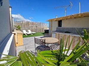 a patio with a table and chairs on a roof at Hôtel Quai d'Azur in Le Grau-du-Roi