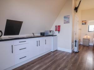 a kitchen with white cabinets and a sink at Cabin 6 An Mhucais in Gortahork +17 photos