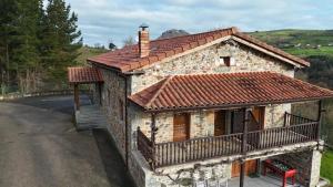 a small stone house with a balcony on a road at Apartamentos La Barcenilla in Herada