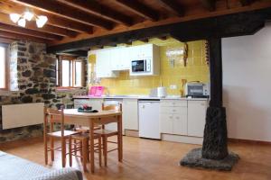a kitchen with white cabinets and a table and chairs at Apartamentos La Barcenilla in Herada