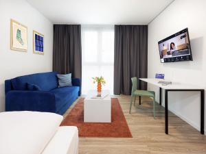 a living room with a blue couch and a table at smartments Frankfurt Airport in Frankfurt