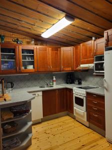 a kitchen with wooden cabinets and a white stove top oven at Huvila Vuosselin Nuppu in Kuusamo