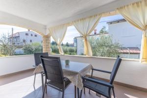 a table and chairs on a balcony with windows at Apartments Koraca in Poreč