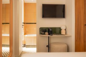 a room with a table and a television on the wall at Salvia Paris in Paris
