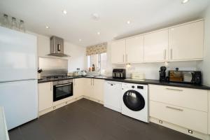 a kitchen with white cabinets and a washer and dryer at Fionas Cottage in Crieff