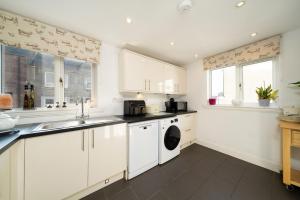 a white kitchen with a sink and a dishwasher at Fionas Cottage in Crieff