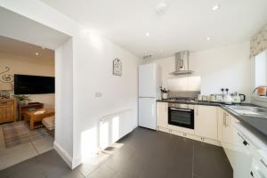 a kitchen with white cabinets and a white refrigerator at Fionas Cottage in Crieff