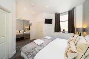 a white bedroom with a bed and a mirror at Fionas Cottage in Crieff +25 photos