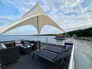 a deck with chairs and an umbrella on a boat at Floatinghouse Möwenblick - LP1 in Vetschau