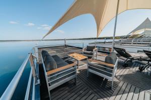 a deck of a boat with chairs and an umbrella at Floatinghouse Seelenbaumler - LP13 in Vetschau