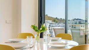 a table with plates and glasses and a vase with flowers at ALLONBAY dream apartment in Villajoyosa