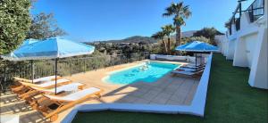 a swimming pool with chairs and umbrellas on a patio at La Bohem'Azur Villa Golfe St Tropez 170m2 5 chambres Piscine Spa Magnifique Vue Dégagée Déco Bohème Chic in Sainte-Maxime