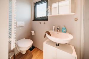 a white bathroom with a toilet and a sink at Floatinghouse Enola in Fürstenberg +5 photos