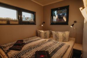 a bedroom with a bed with two pillows and two windows at Floatinghouse Enola in Fürstenberg