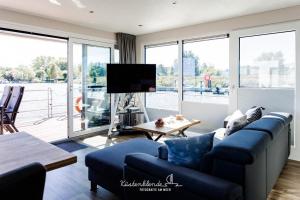 a living room with a blue couch and a tv at Floatinghouse Arielle in Ribnitz-Damgarten