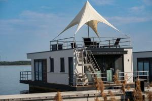 a house boat with a white sail on the water at Floatinghouse Neptun - LP3 in Vetschau