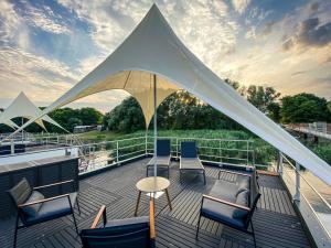 a deck with chairs and a tent on a boat at Floatinghouse Neptun - LP3 in Vetschau