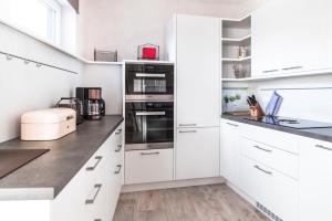 a white kitchen with white cabinets and appliances at Floatinghouse Möwe 1 - LP1 in Vetschau