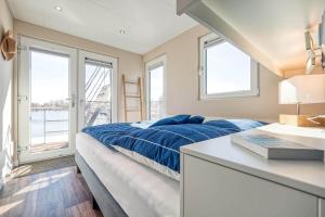 a bedroom with a bed and a sink and windows at Floatinghouse Mein Lieblingsboot in Ribnitz-Damgarten
