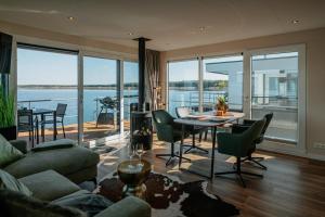 a living room with a table and chairs and a view of the water at Floatinghouse Seeblick - LP7 in Vetschau