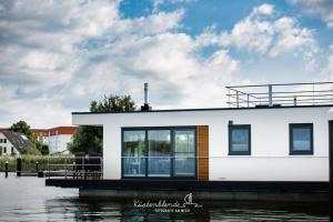a house on a dock next to a body of water at Floatinghouse Dory in Ribnitz-Damgarten +19 photos