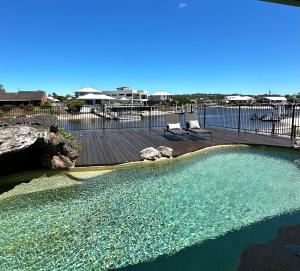 a large pool of water with two chairs on a deck at Waterfront Retreat Mooloolaba in Mooloolaba