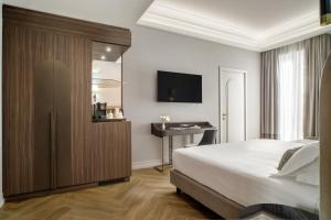a bedroom with a bed and a desk and a television at Aria Palace by OMNIA hotels in Rome