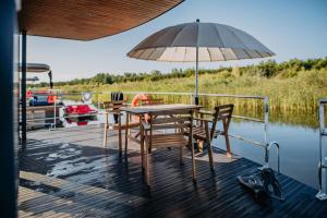 a table and chairs on a dock with an umbrella at Floatinghouse Möwe 4 - LP4 in Vetschau