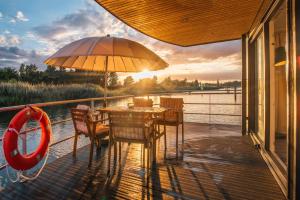 a deck with a table and chairs and an umbrella at Floatinghouse Möwe 4 - LP4 in Vetschau