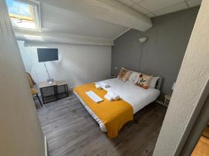 a bedroom with a large bed with a yellow blanket at Le central in Balaruc-les-Bains