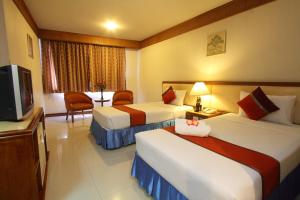 ein Hotelzimmer mit zwei Betten und einem Fernseher in der Unterkunft Silom Avenue Inn in Bangkok