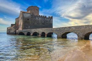 an old castle on the water with a bridge at Casetta Amati 2 in Nettuno