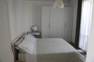 a white bedroom with a bed and a mirror at Casetta Amati 2 in Nettuno