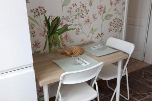 a dining room table with white chairs and a flowery wallpaper at Casetta Amati 2 in Nettuno