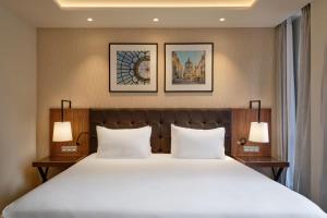 a bedroom with a large white bed with two lamps at Eurostars Avenue Louise in Brussels