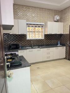 a kitchen with white cabinets and a counter top at Shana Homes in Karsana