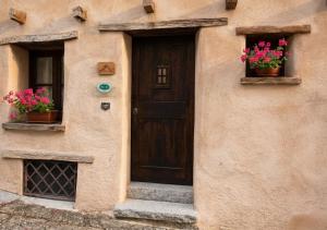 a building with a door and two windows with flowers at S'Ispera B&B, Home Restaurant, Autentiche Esperienze Sarde in Fonni