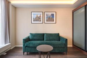 a living room with a green couch and a table at Eurostars Avenue Louise in Brussels
