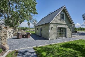 a small green building with a patio and a table at Bottengarn Boutique Guesthouse - Farm in Igaküla