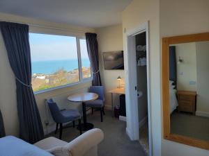 a room with a bed and a table and a window at Geckos Rest in Newquay