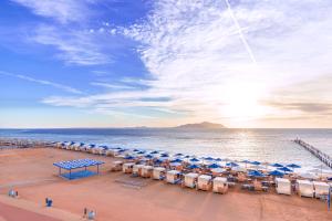 a beach with chairs and umbrellas and the ocean at Pickalbatros Palace Sharm "Aqua Park"- All inclusive in Sharm El Sheikh
