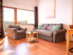a living room with a couch and a table at SONNENSEITE Schonach - Private Infrarot-Sauna - Schwarzwald-Panoramablick - 2 separate Schlafzimmer - Ruhige Lage am Waldrand in Schonach