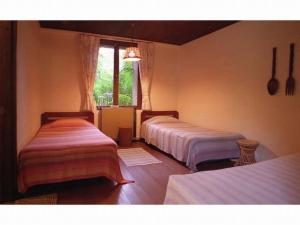 a bedroom with two beds and a window at Pension Iriomote in Iriomote
