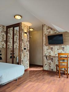 a bedroom with a stone wall with a bed and a tv at Hotel Puerto de Candás in Candás