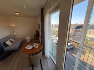 ein Wohnzimmer mit einem Tisch und einem großen Fenster in der Unterkunft Hotel Rasch in Bergen aan Zee
